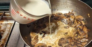 adding cream sauce to a pan