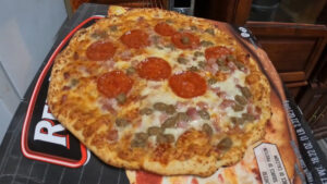 Frozen pizza cooked in a toaster oven with golden brown crust and melted cheese