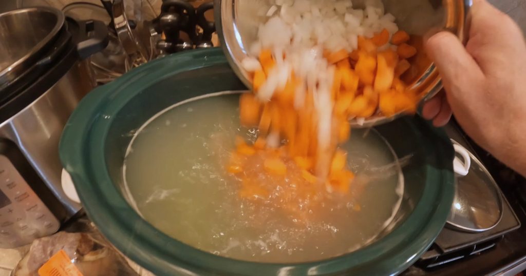 adding carrots and onions to the soup