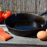 seasoned cast iron skillet with salmon, tomatoes, garlic, and eggs, the foods people say never to cook in cast iron