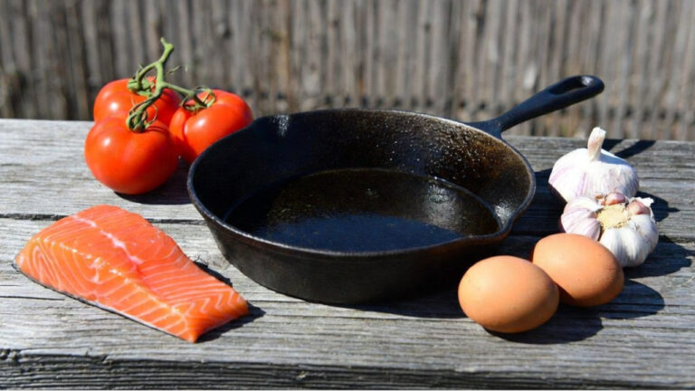 seasoned cast iron skillet with salmon, tomatoes, garlic, and eggs, the foods people say never to cook in cast iron